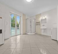 Badezimmer in einem Einfamilienhaus mit Duschkabine, Waschmaschine und großen Türen zur Terrasse.