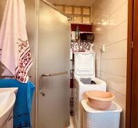 Badezimmer in einer 3-Zimmer-Wohnung mit Waschbecken, Duschkabine, Waschmaschine und Regal.