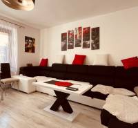 Wohnzimmer in einer 3-Zimmer-Wohnung, mit einem Sofa und einem Boden in Holzoptik.