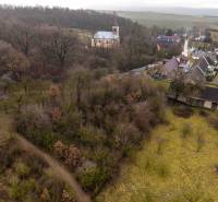 Gemerské Teplice erfassen Erholungsgrundstücke mit waldreicher Landschaft und einer Kirche im Hintergrund.