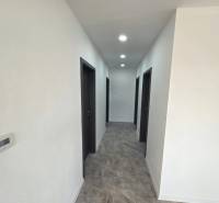 Flur in einem Einfamilienhaus mit dunklen Türen und Bodenbeleuchtung in Holzoptik.