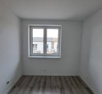 Ein Zimmer in einem Einfamilienhaus mit einem Holzboden und einem großen Fenster.