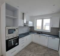 Küche in einem Einfamilienhaus mit weißen Schränken und eingebauten Geräten.