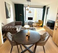 Wohnzimmer mit Sofa, Esstisch und Holzboden in einer Zweizimmerwohnung.