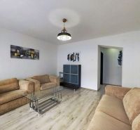 Wohnzimmer in einer 3-Zimmer-Wohnung mit Sofas und Glastisch, Boden mit Holzdekor.