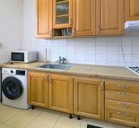 Küche in einer 3-Zimmer-Wohnung mit Holzschränken und Geräten, einschließlich Waschmaschine und Mikrowelle.