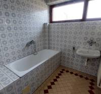 Badezimmer mit gemusterten Fliesen, Badewanne, Waschbecken und Heizkörper in einem Einfamilienhaus.