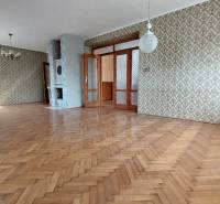 Ein geräumiges Zimmer mit Holzboden und gemusterten Tapeten in einem Einfamilienhaus.