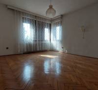 Ein geräumiges Zimmer mit Holzboden, weißen Wänden und Vorhängen in einem Einfamilienhaus.