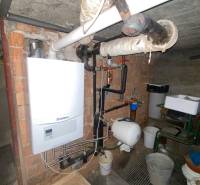 Ein Gaskessel im Keller eines Einfamilienhauses mit Rohrleitungen und einem Wasserspeicher an der Wand.
