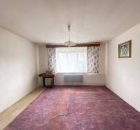 Ein Zimmer in einem Einfamilienhaus mit einem violetten Teppich, Blumenvorhängen und einem Kronleuchter.