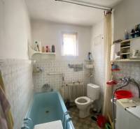 Badezimmer in einem Einfamilienhaus mit Badewanne, Waschmaschine und Fenster.