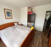 Schlafzimmer in einer 4-Zimmer-Wohnung mit Holzboden und Holzbett.