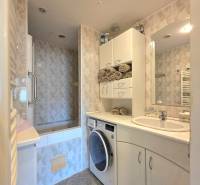 Badezimmer in einer 4-Zimmer-Wohnung mit Waschmaschine, Badewanne und heller Fliesen.