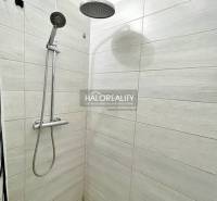 Duschkabine mit weißen Fliesen in einer 2-Zimmer-Wohnung.