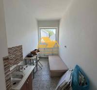 Kleine Garçonnière mit Waschbecken, Tisch und Liege, geeignet für praktisches Wohnen.