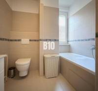 Badezimmer in einer Ferienwohnung mit Badewanne, Toilette und modernen Fliesen.