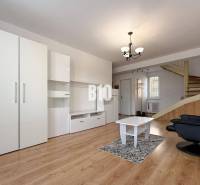 Wohnzimmer in einer Ferienwohnung mit weißen Möbeln und einem Boden in Holzoptik.