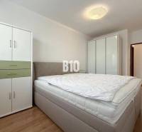 Helles Zimmer in einer Ferienwohnung mit Bett, Kleiderschränken und Holzboden.