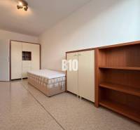 Helles Zimmer in einer Ferienwohnung mit Bett, Schrank und Regalsystem.