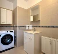 Badezimmer mit Waschmaschine, Waschbecken und Schränken im Ferienapartment.