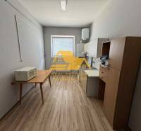 Einfache Einrichtung eines Einzimmerapartments mit Küchenzeile und Holzboden.