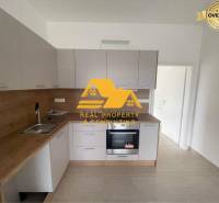Küche in einer 3-Zimmer-Wohnung mit Holzdekor-Arbeitsplatte und weißen Schränken.