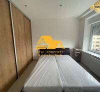 Schlafzimmer in einer 3-Zimmer-Wohnung mit Bett, Einbauschrank und Fenster mit Aussicht.