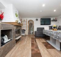 Wohnzimmer mit Kamin, Sitzgarnitur und Tisch; Boden mit Holzdekor.