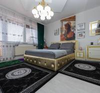 Ein Schlafzimmer in einem Einfamilienhaus mit einem gepolsterten Bett und dekorativen Vorhängen.