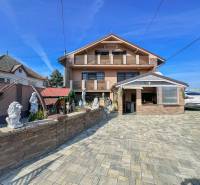 Ein Einfamilienhaus in Dvorníky mit einem großen Hof, Skulpturen und einer Garage für ein Auto.