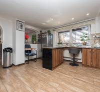 Küche in einem Einfamilienhaus mit angenehmer Atmosphäre, Boden mit Holzdekor, Bar-Sitzgelegenheit.