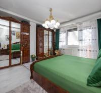 Schlafzimmer in einem Einfamilienhaus mit Holzspiegelschränken und grüner Bettwäsche.