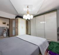 Schlafzimmer mit Bett, weißem Schrank, Teppichen und Licht in einem Einfamilienhaus.