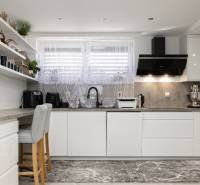 Eine Küche in einem Einfamilienhaus mit weißen Möbeln, dekorativen Regalen und stilvollen Geräten.