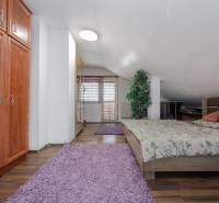 Schlafzimmer in einem Einfamilienhaus mit Bett, Schrank und Boden in Holzoptik.