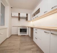 Küche mit Geräten, weißen Schränken und Holzboden in einer 2-Zimmer-Wohnung.