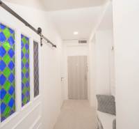 Flur mit Buntglastüren, Kleiderhaken und Holzelementen in einer 2-Zimmer-Wohnung.