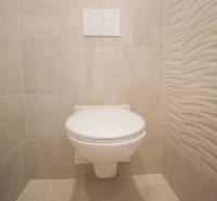 Badezimmer in einer 2-Zimmer-Wohnung mit weißer Toilette und hellen Fliesen.