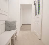 Ein heller Flur mit weißen Möbeln und dekorativen Kissen in einer 2-Zimmer-Wohnung.