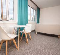 Wohnzimmer mit Tisch und Stühlen in einer 4-Zimmer-Wohnung, leuchtende Vorhänge, heller Teppich.