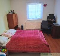 Ein Schlafzimmer in einem Einfamilienhaus mit Bett, Schreibtisch und einem Boden in Holzoptik.
