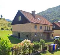 Ein Einfamilienhaus in Liptovské Revúce mit rotem Dach, Garten und einem Blumenzaun.