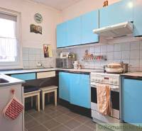 Küche in einem Einfamilienhaus mit blauen Schränken und einer gefliesten Wand.