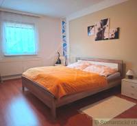 Ein Schlafzimmer in einem Einfamilienhaus mit Bett, Dekoration und einem Boden in Holzoptik.