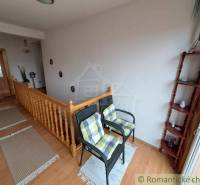 Innenraum eines Einfamilienhauses mit Treppe, Stühlen und Boden in Holzoptik.