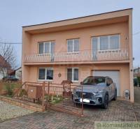 Ein Einfamilienhaus in Veľké Ripňany mit einem Balkon und einem Auto in der Einfahrt.