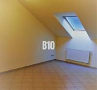 Ein Dachzimmer mit Dachfenster und Fliesen, geeignet für Büros.