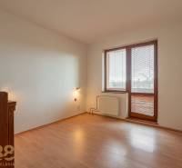 Ein Zimmer mit einem Boden in Holzoptik in einer Wohnung mit fünf oder mehr Zimmern, helle Wände, großes Fenster.