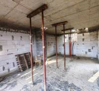 Das Innere der Hütte im Bau mit temporären Stützen, unverkleideten Ziegeln und Baumaterial.